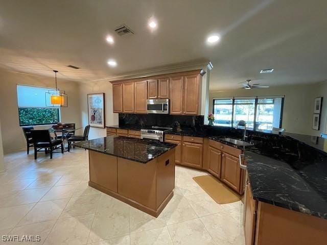 kitchen featuring stainless steel appliances, ceiling fan, sink, dark stone countertops, and hanging light fixtures