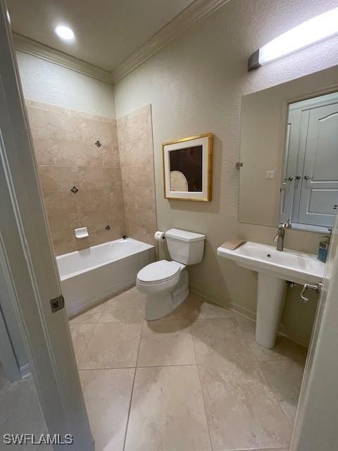 bathroom with tile patterned floors, toilet, ornamental molding, and tiled shower / bath