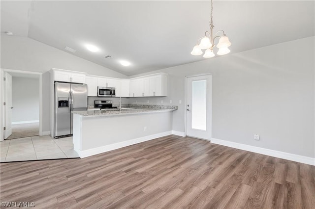 kitchen featuring kitchen peninsula, light wood-type flooring, stainless steel appliances, decorative light fixtures, and white cabinetry