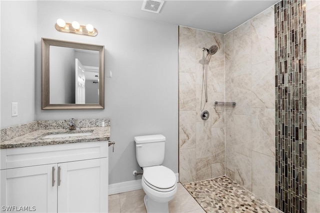 bathroom featuring tile patterned flooring, vanity, toilet, and a tile shower