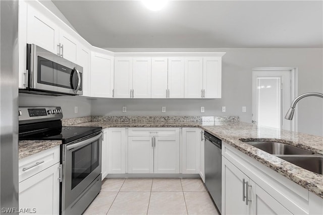 kitchen with light stone countertops, white cabinetry, sink, stainless steel appliances, and light tile patterned floors