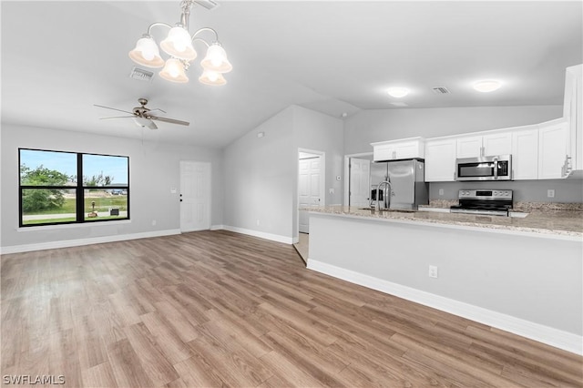 kitchen with lofted ceiling, white cabinets, ceiling fan with notable chandelier, light wood-type flooring, and appliances with stainless steel finishes