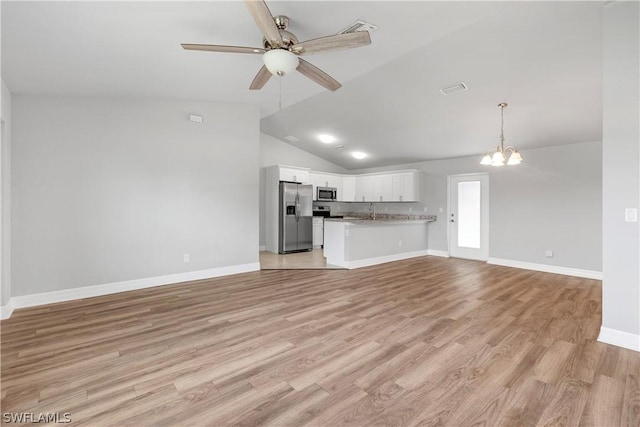 unfurnished living room featuring ceiling fan with notable chandelier, vaulted ceiling, and light wood-type flooring