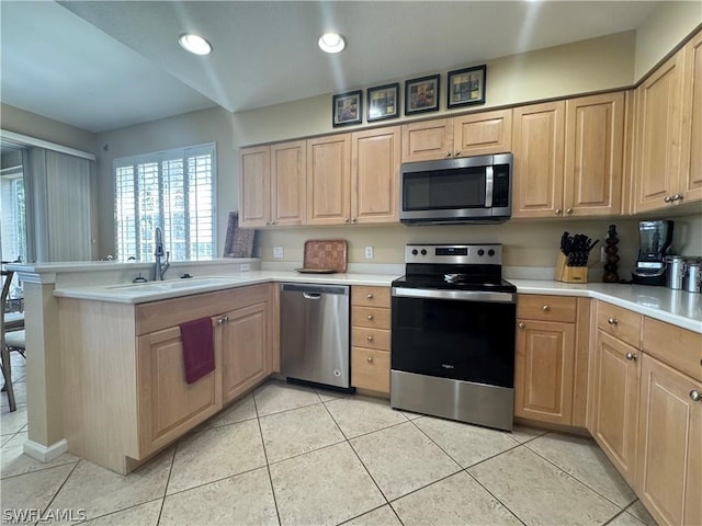 kitchen featuring kitchen peninsula, light tile flooring, light brown cabinetry, sink, and appliances with stainless steel finishes