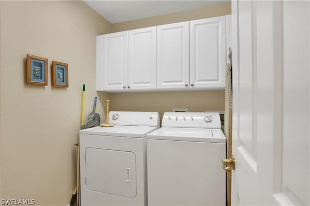 clothes washing area with washing machine and clothes dryer and cabinets