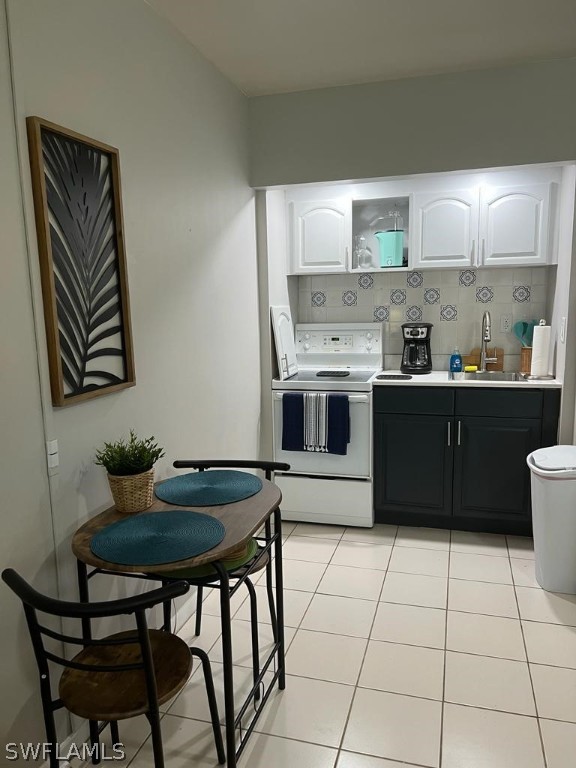 kitchen with white cabinetry, light tile patterned flooring, decorative backsplash, and white range with electric stovetop