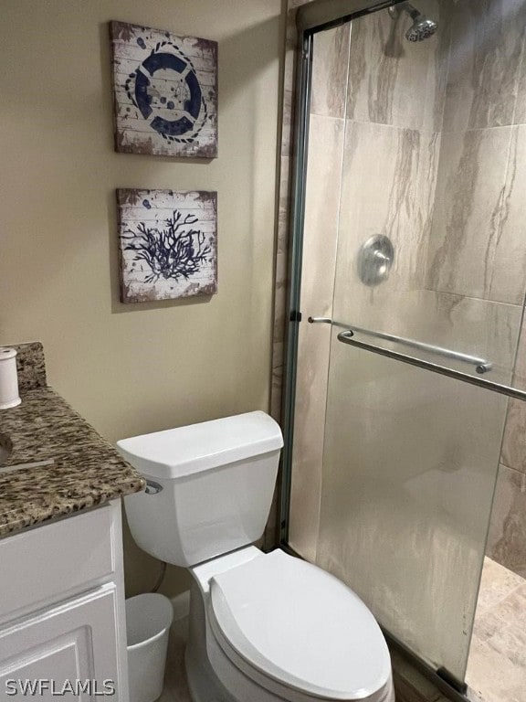 bathroom with vanity, a shower with door, and toilet