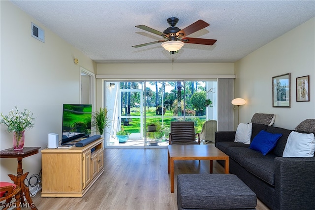 living room with a textured ceiling, ceiling fan, and light hardwood / wood-style flooring