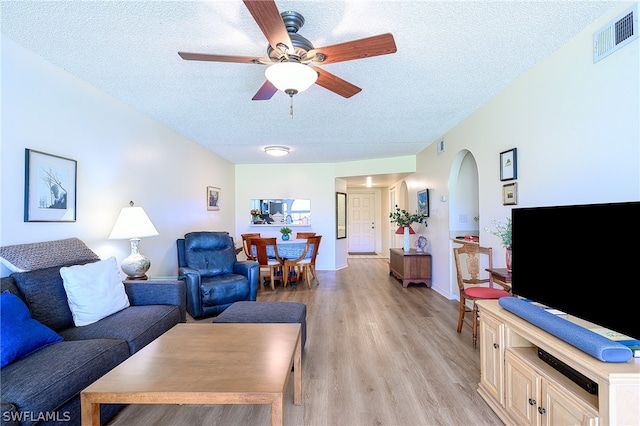 living room with ceiling fan, light hardwood / wood-style floors, and a textured ceiling