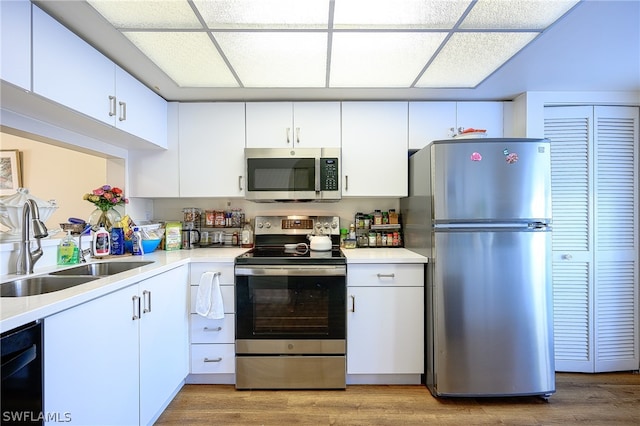 kitchen with sink, hardwood / wood-style floors, white cabinets, and appliances with stainless steel finishes