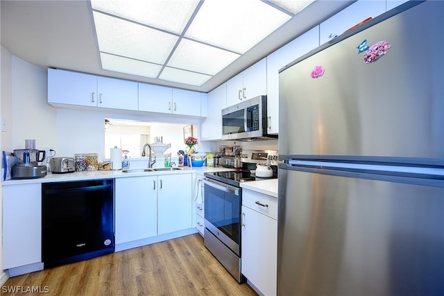 kitchen with stainless steel appliances, white cabinets, light wood-type flooring, and sink