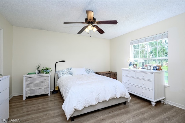 bedroom featuring ceiling fan, multiple windows, a textured ceiling, and hardwood / wood-style flooring