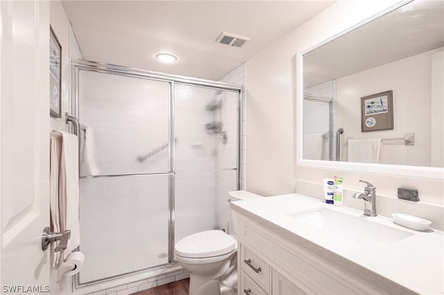 bathroom with a shower with door, toilet, and vanity with extensive cabinet space