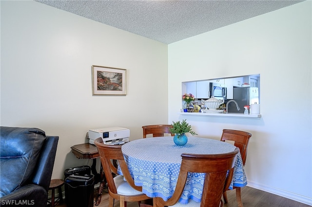 dining space featuring sink, a textured ceiling, and hardwood / wood-style flooring