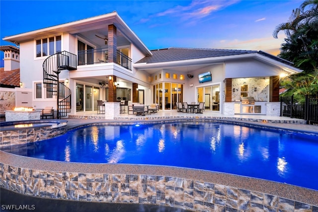 rear view of house with area for grilling, a swimming pool with hot tub, a balcony, and a patio area