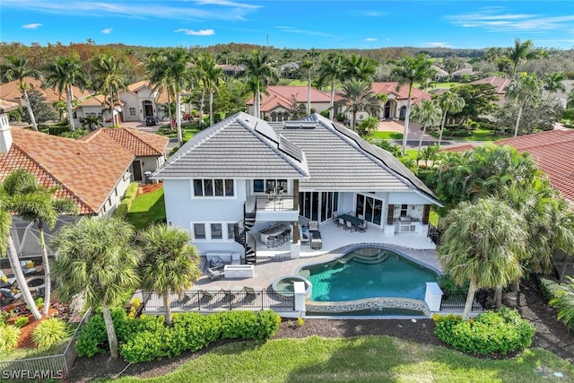 back of property featuring a balcony, a fenced in pool, and a patio area