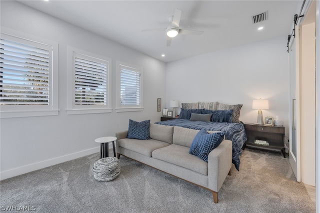 carpeted bedroom featuring ceiling fan and a barn door