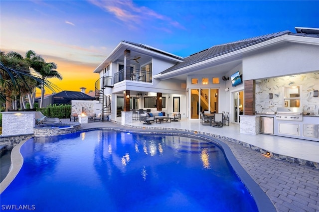 pool at dusk featuring an outdoor living space, an in ground hot tub, area for grilling, exterior kitchen, and a patio