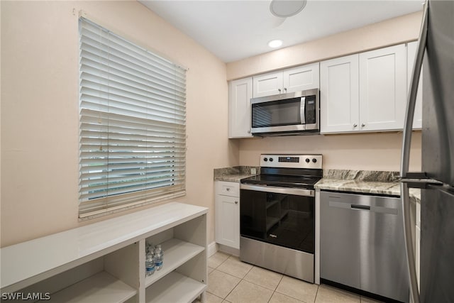 kitchen featuring light tile flooring, stone countertops, white cabinetry, and appliances with stainless steel finishes