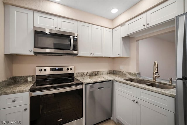 kitchen featuring a sink, light stone counters, white cabinetry, recessed lighting, and stainless steel appliances