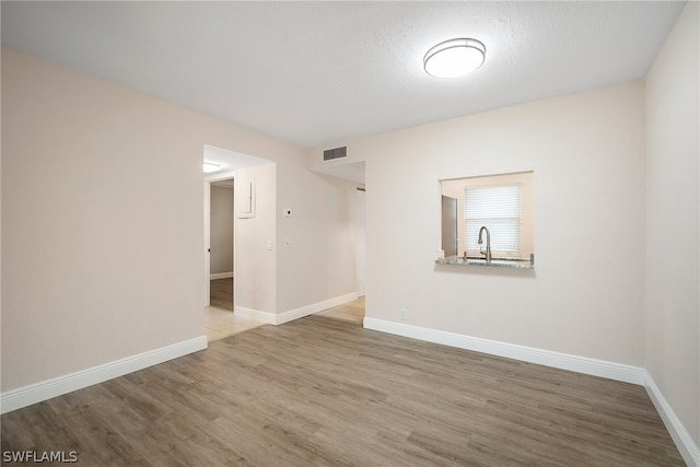 unfurnished room with hardwood / wood-style floors and sink