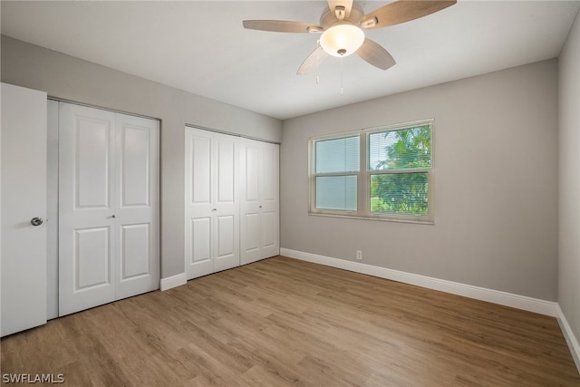 unfurnished bedroom with two closets, ceiling fan, and light wood-type flooring