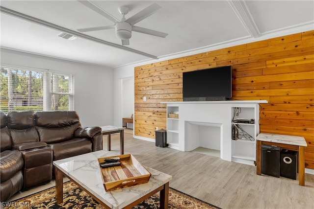 living room featuring ceiling fan, wooden walls, crown molding, and light hardwood / wood-style flooring