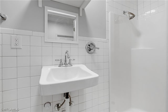 bathroom featuring a tile shower, tile walls, and sink