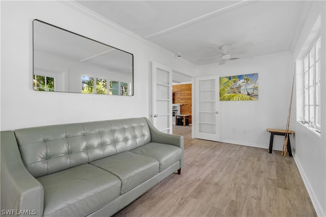 living room with crown molding, built in shelves, ceiling fan, and light hardwood / wood-style flooring