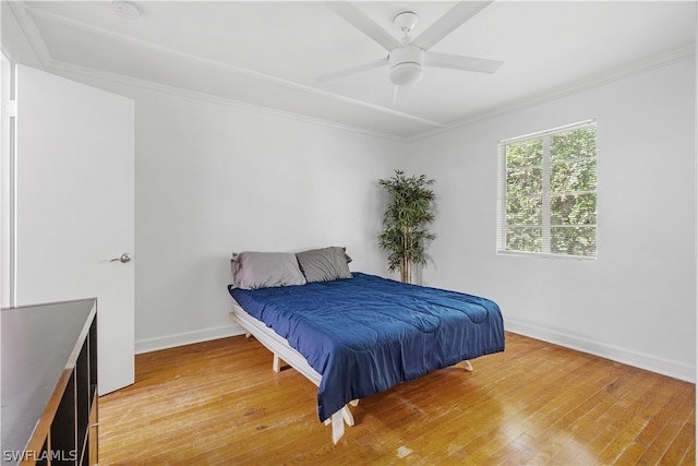 bedroom featuring wood-type flooring, crown molding, and ceiling fan