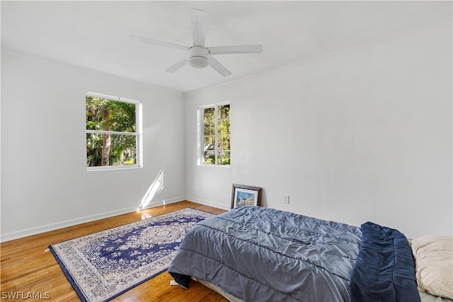 bedroom featuring wood-type flooring, ornamental molding, and ceiling fan