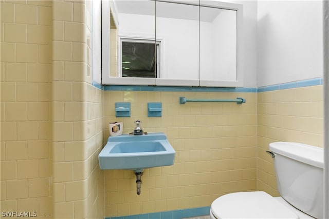 bathroom with tile walls, toilet, and sink