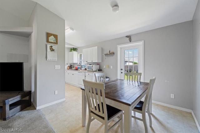 tiled dining space featuring sink and vaulted ceiling