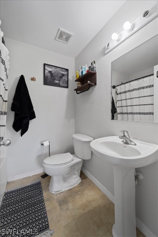 bathroom featuring tile flooring, shower / tub combo with curtain, and toilet