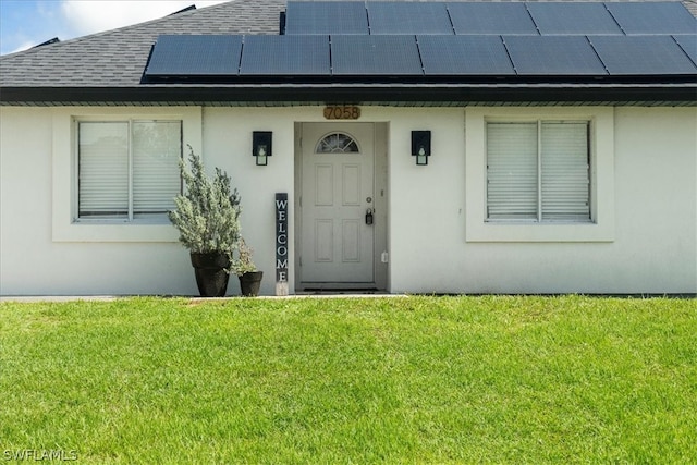 property entrance featuring solar panels and a lawn