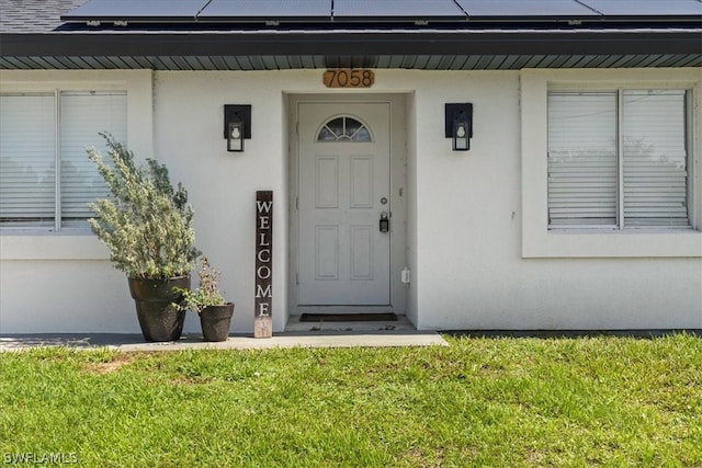 view of exterior entry featuring solar panels and a yard