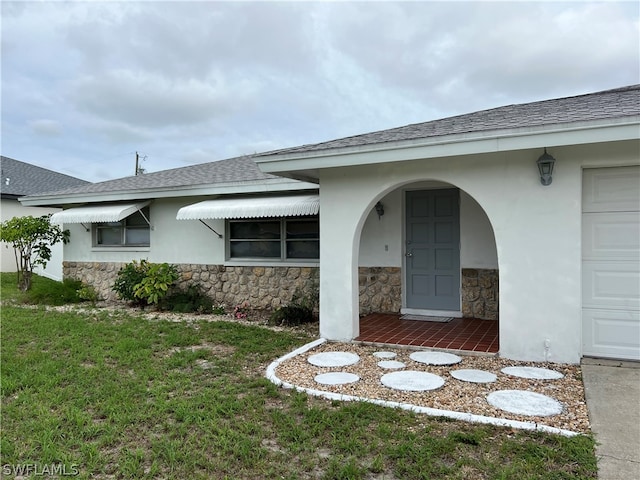 property entrance with a garage and a lawn