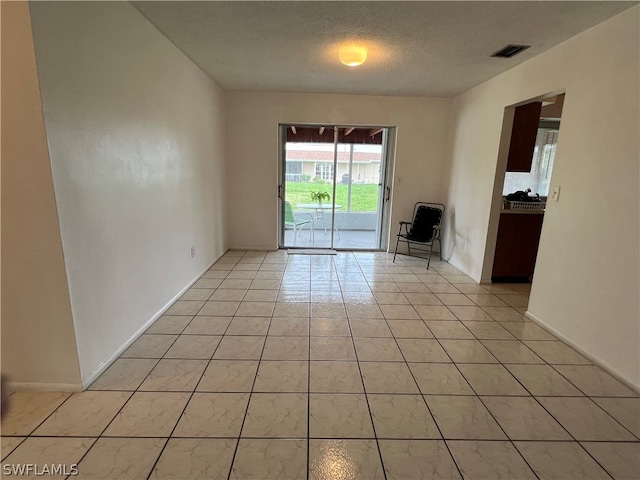 spare room with light tile patterned floors and a textured ceiling