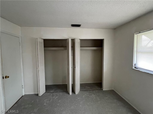 unfurnished bedroom featuring a textured ceiling and two closets