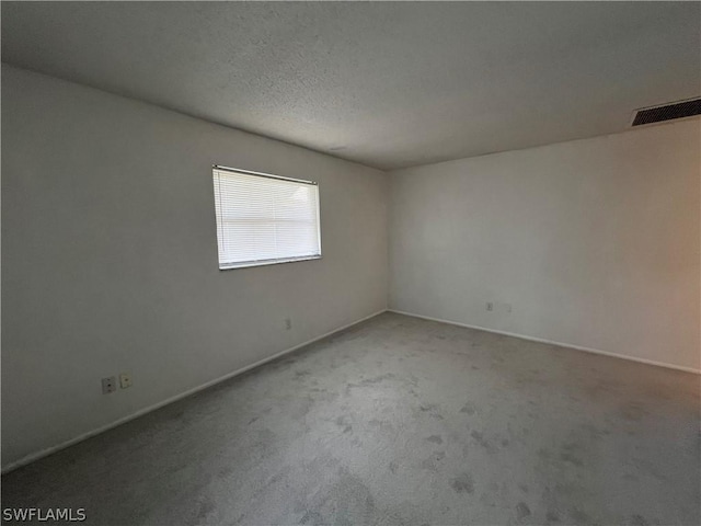 empty room with light colored carpet and a textured ceiling