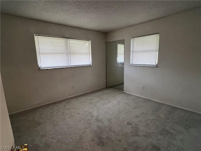 spare room featuring dark carpet and a textured ceiling