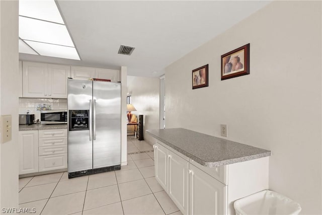 kitchen with decorative backsplash, white cabinets, stainless steel appliances, and light tile patterned floors