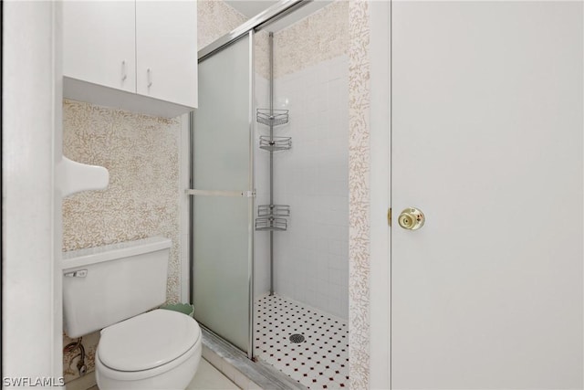 bathroom featuring toilet and a shower with door