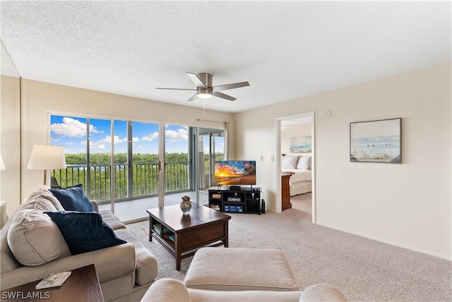 living room with ceiling fan, a textured ceiling, and carpet floors