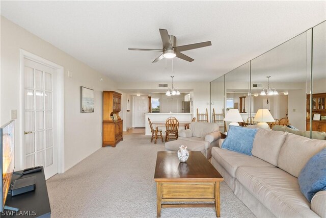 carpeted living room with ceiling fan with notable chandelier