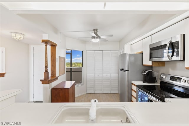 kitchen with appliances with stainless steel finishes, sink, white cabinets, and ceiling fan