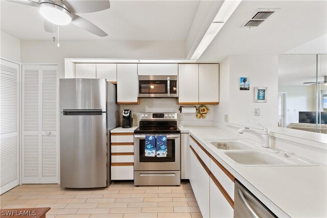 kitchen featuring ceiling fan, light tile flooring, sink, white cabinets, and appliances with stainless steel finishes