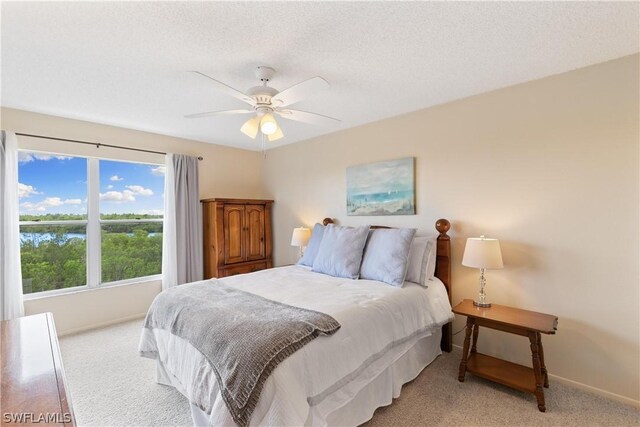 bedroom with ceiling fan, a textured ceiling, and light colored carpet