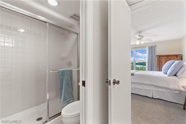 bathroom with a shower with door, ceiling fan, a textured ceiling, and toilet