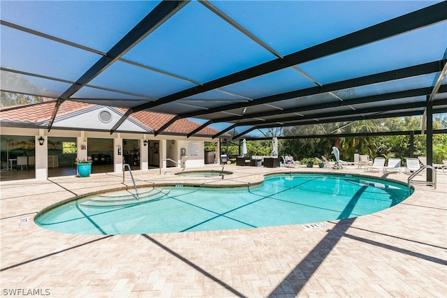 view of swimming pool featuring a community hot tub, a patio, and a lanai